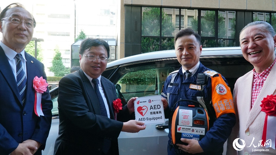 ボランティアと共にAED搭載車両ステッカーを貼るゲスト（撮影・蒋暁辰）。