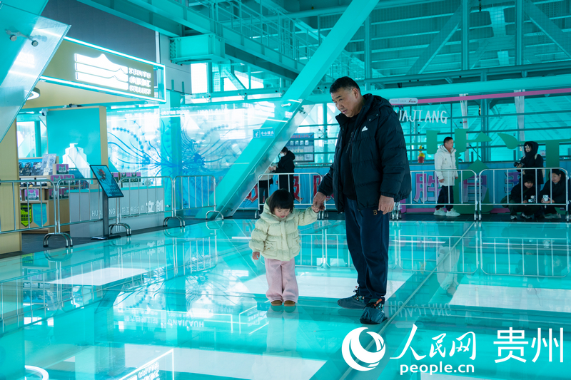 橋に設置されているアクティビティを体験する子供連れの観光客（撮影・陽茜）。