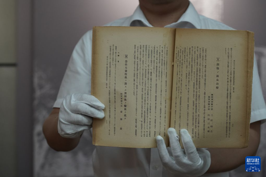 1940年8月1日発行の『軍医団雑誌』原本を示す侵華日軍第七三一部隊罪証陳列館の研究員（6月23日撮影・何山）