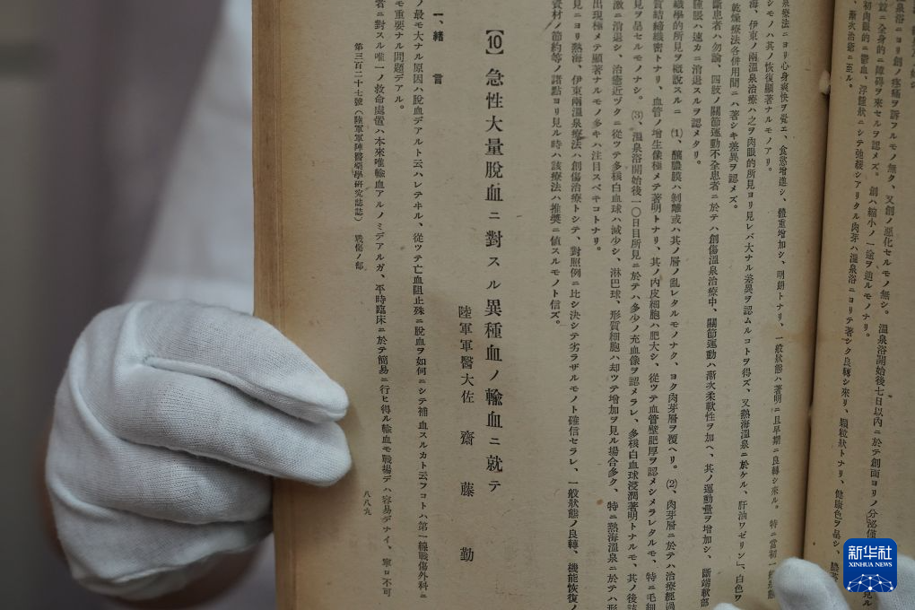 1940年8月1日発行の『軍医団雑誌』原本を示す侵華日軍第七三一部隊罪証陳列館の研究員（6月23日撮影・何山）
